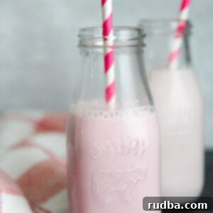 Fresh Strawberry Milk Delight 4 two milk jugs filled with strawberry milk and pink and white straws.