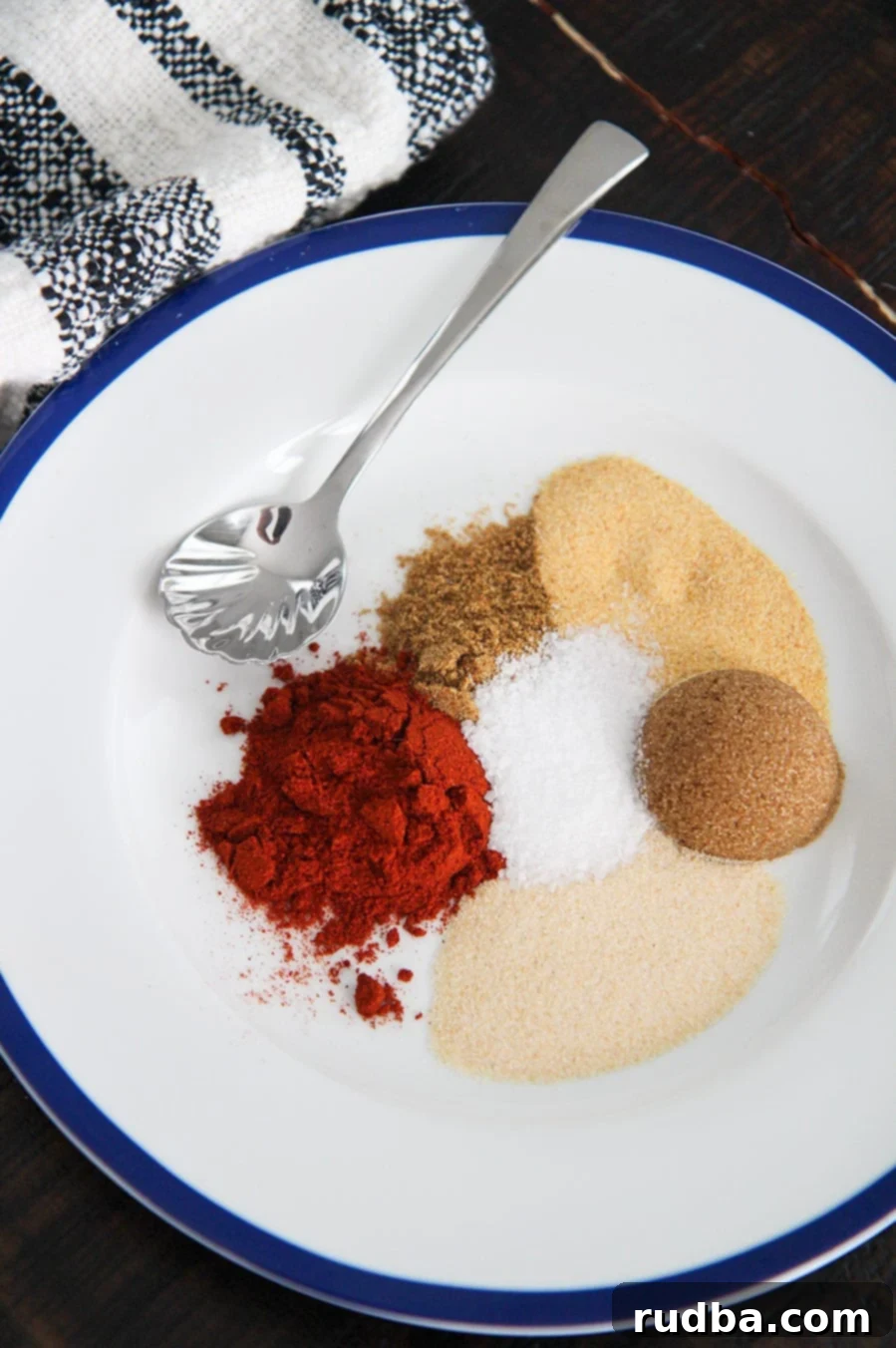 brown sugar and 5 spices on a white plate with a small spoon and towel on the side. 