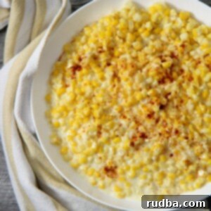Golden Cream Corn Delight 5 creamed corn in a white plate with a yellow and white kitchen towel on the side.