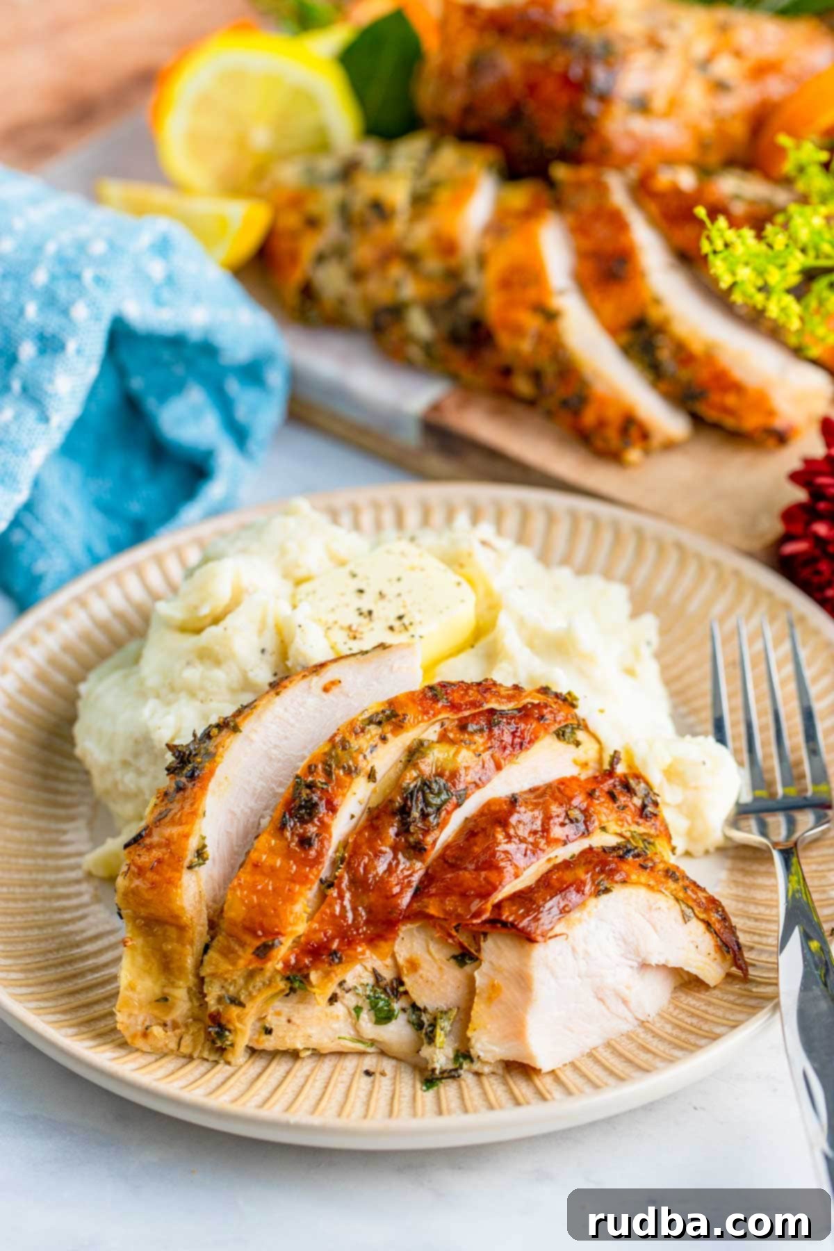 Sliced juicy roast turkey breast served on a plate with creamy mashed potatoes and a fork, ready to eat.