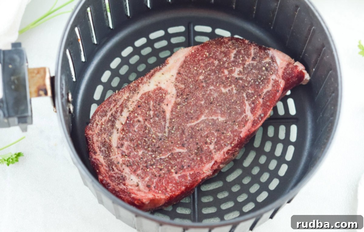 raw rib eye steak in the air fryer basket. 