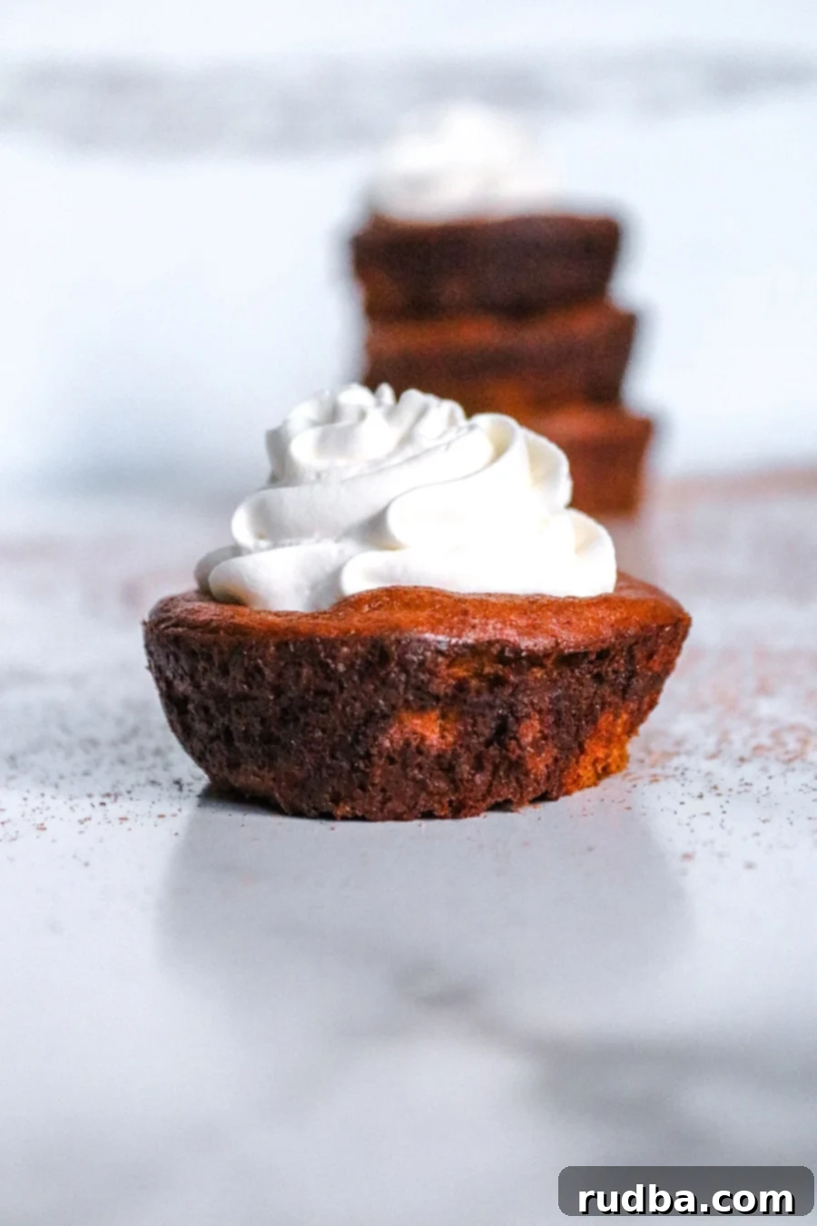 keto mini pumpkin pie up close with whipped cream on top. 