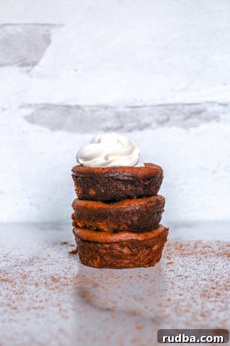three mini pumpkin pies stacked on top of each other with whipped cream. 