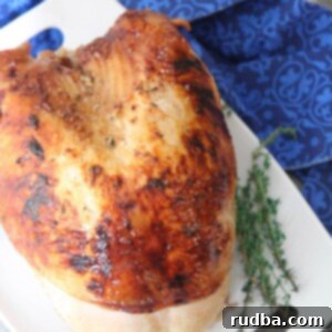 Maple Glazed Turkey Breast 5 maple glazed turkey breast on a white platter with fresh thyme on the side and a blue towel underneath the platter.