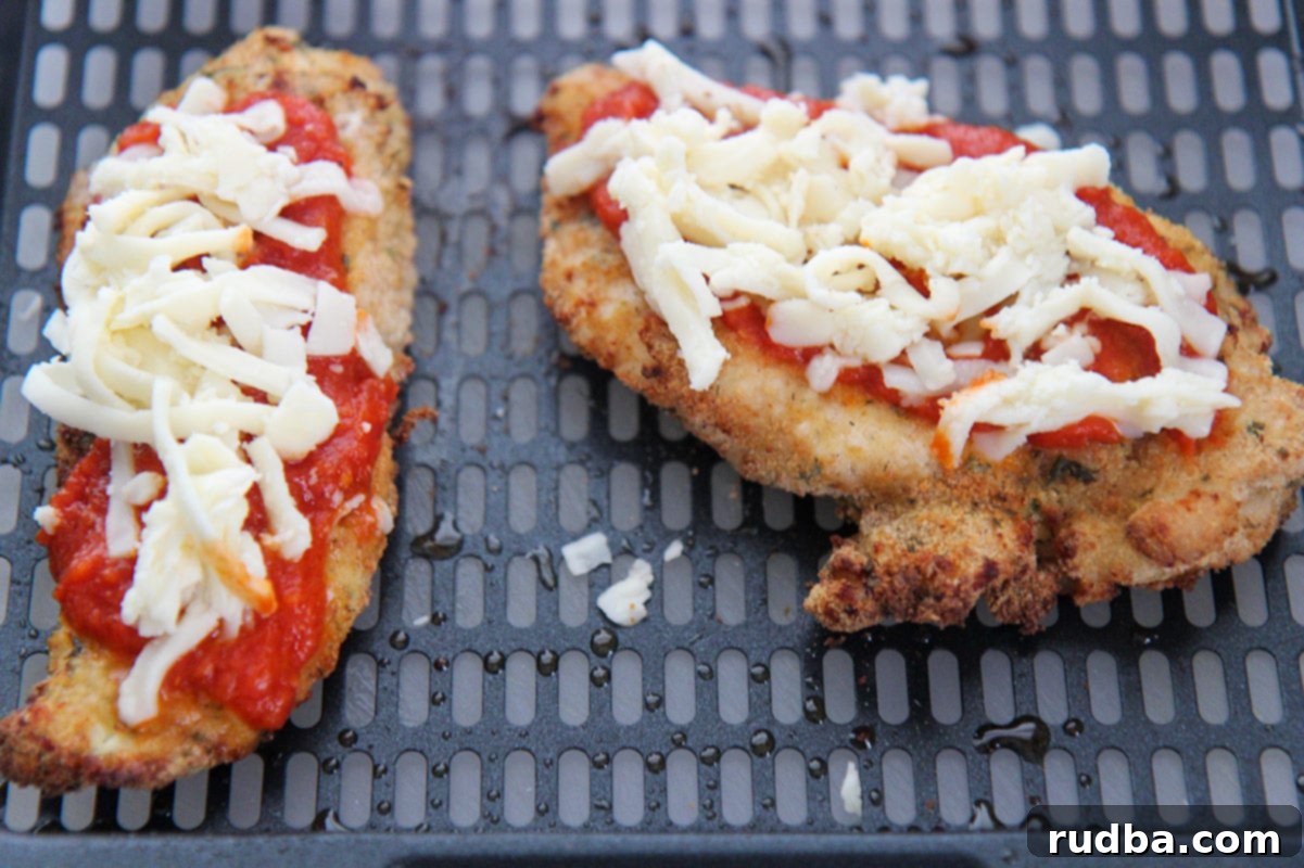 two chicken breasts with sauce and shredded cheese on top. 