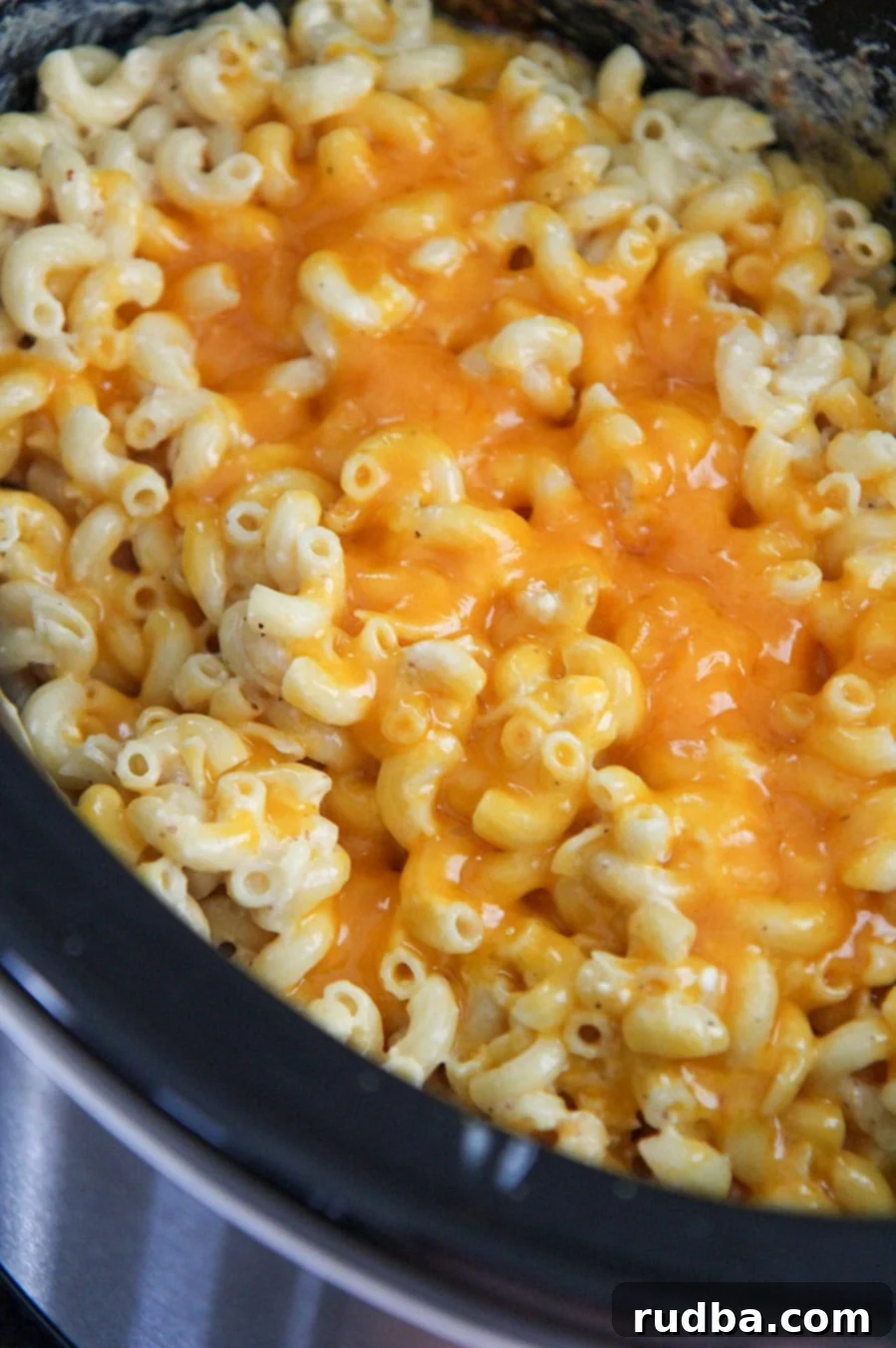 Mac and cheese in the crockpot with yellow melted cheese on top, ready to serve
