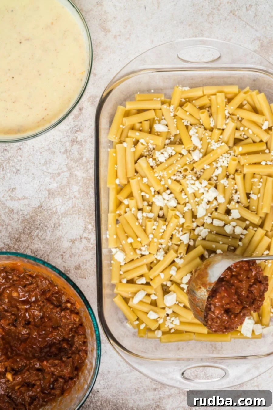 cooked ziti with cheese, a ladle of meat sauce, one bowl of bechamel sauce, and one bowl of meat sauce.