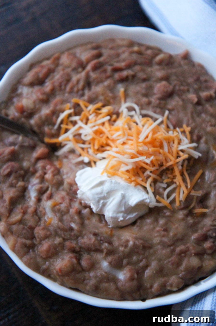beans in a white bowl with sour cream and cheese on top. 