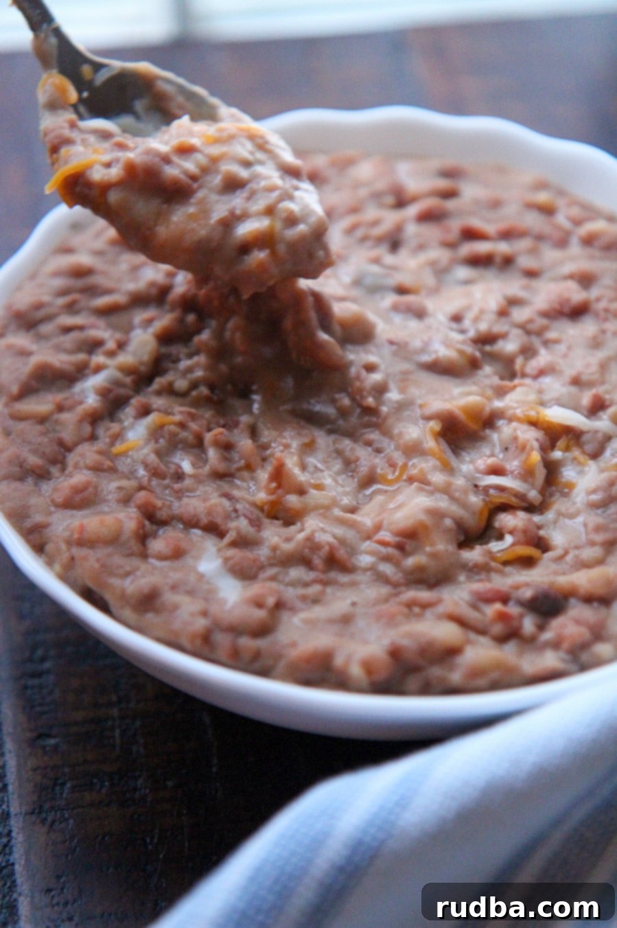 chunky pinto beans with melted cheese and a spoon.