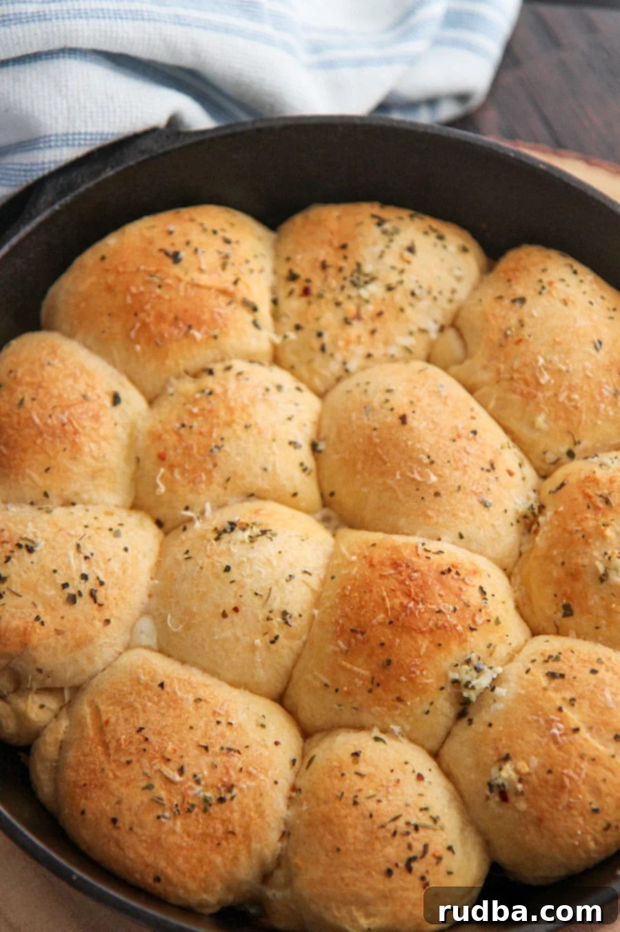 baked cheese stuffed rolls in a cast iron skillet with a blue and white towel on the side.