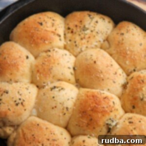 Cheesy Stuffed Rolls 4 baked cheese stuffed rolls in a cast iron skillet with a blue and white towel on the side.