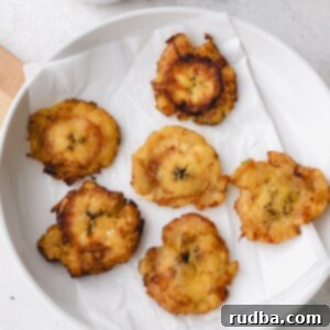 Crispy Tostones 4 6 tostones on a white plate with a side of garlic butter sauce.