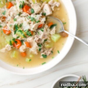 Cozy Turkey Rice Remix Soup 4 leftover turkey and rice soup in a white bowl with fresh rosemary on the side.