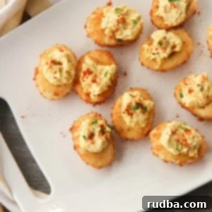 Golden Fried Deviled Delights 4 nine fried deviled eggs on a white platter with a yellow and white towel on the side.