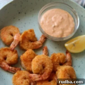 air fried shrimp on a blue plate with a lemon wedge and sauce in a bowl.