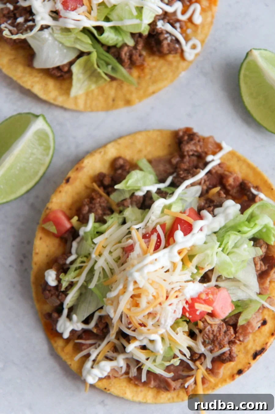 beef tostadas up close with two lime wedges.