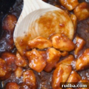 Easy Slow Cooker Orange Chicken 4 orange chicken in the slow cooker with a wooden spoon.