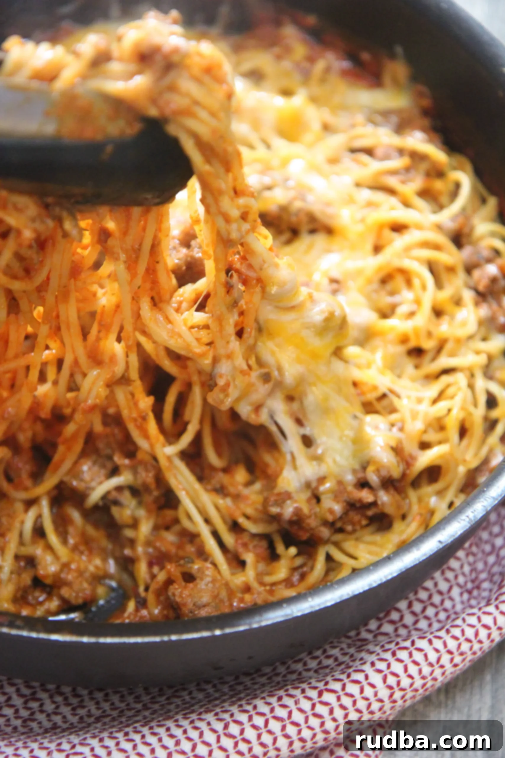 Overhead shot of perfectly seasoned, cheesy taco spaghetti in a skillet, showcasing it as a quick and delicious dinner time solution.