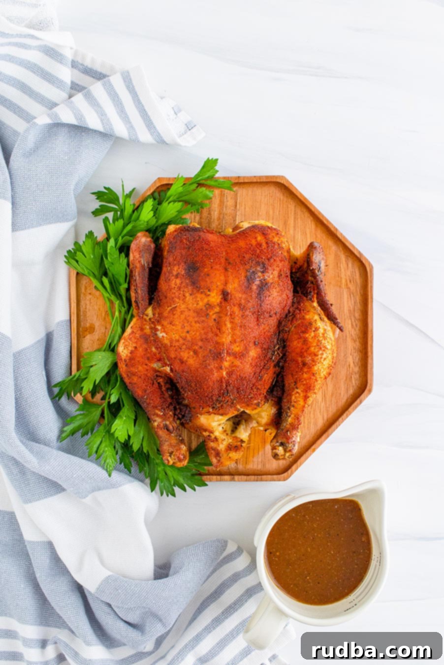 cooked whole chicken on a cutting board with gravy on the side. 