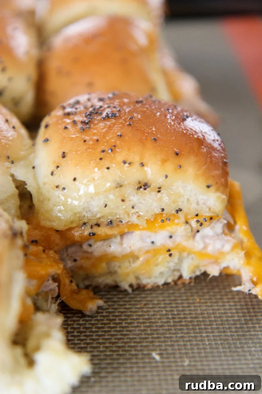 Close-up view of three tuna melt sliders, showing the melted cheese and a hint of the tuna salad peeking out, with a golden-brown top.