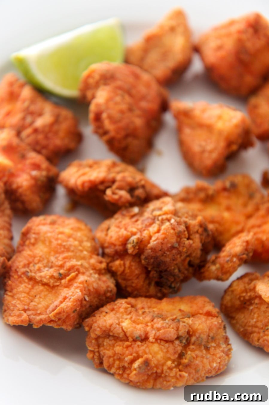 crispy fried chicken bites with a lime wedge up close. 