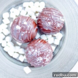 Decadent Salted Caramel Hot Chocolate Bombs 5 three hot chocolate bombs on a plate with mini marshmallows.