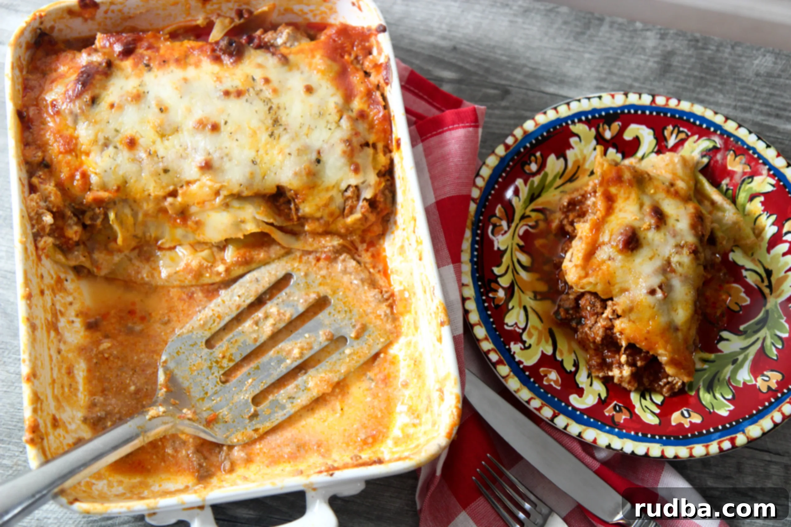 A slice of low-carb cabbage lasagna being served from a white skillet onto a small plate