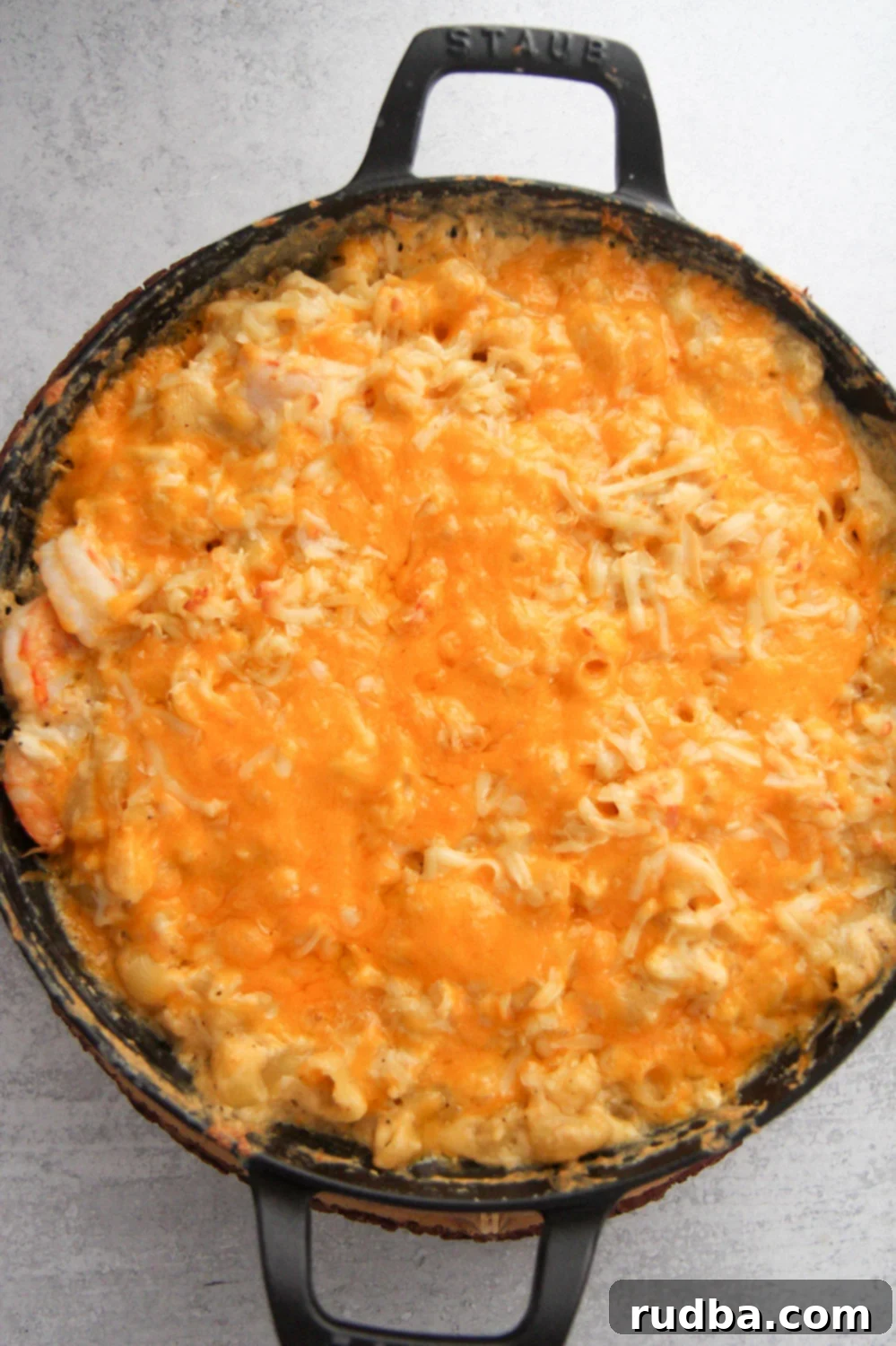 Seafood macaroni and cheese served hot in a black cast iron skillet, garnished with fresh herbs.
