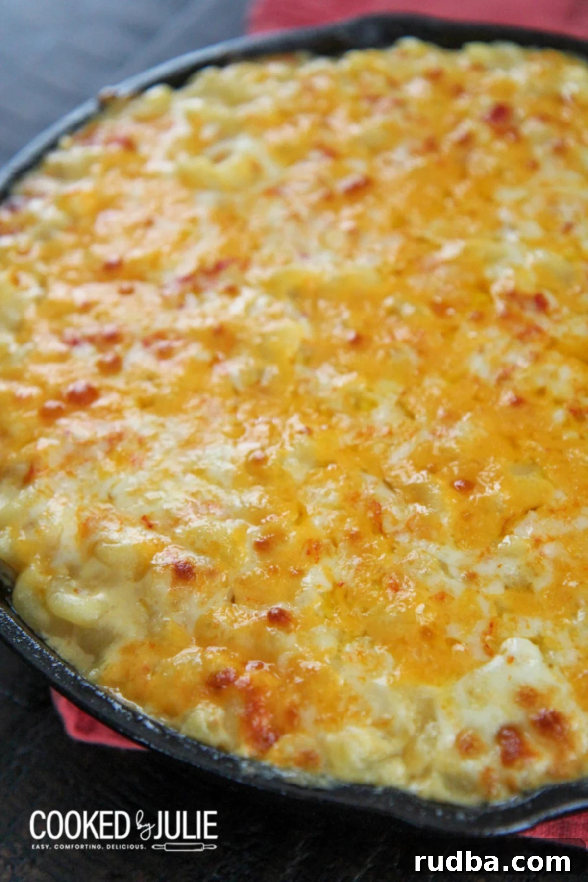 mac and cheese in an iron skillet with a red towel on the side