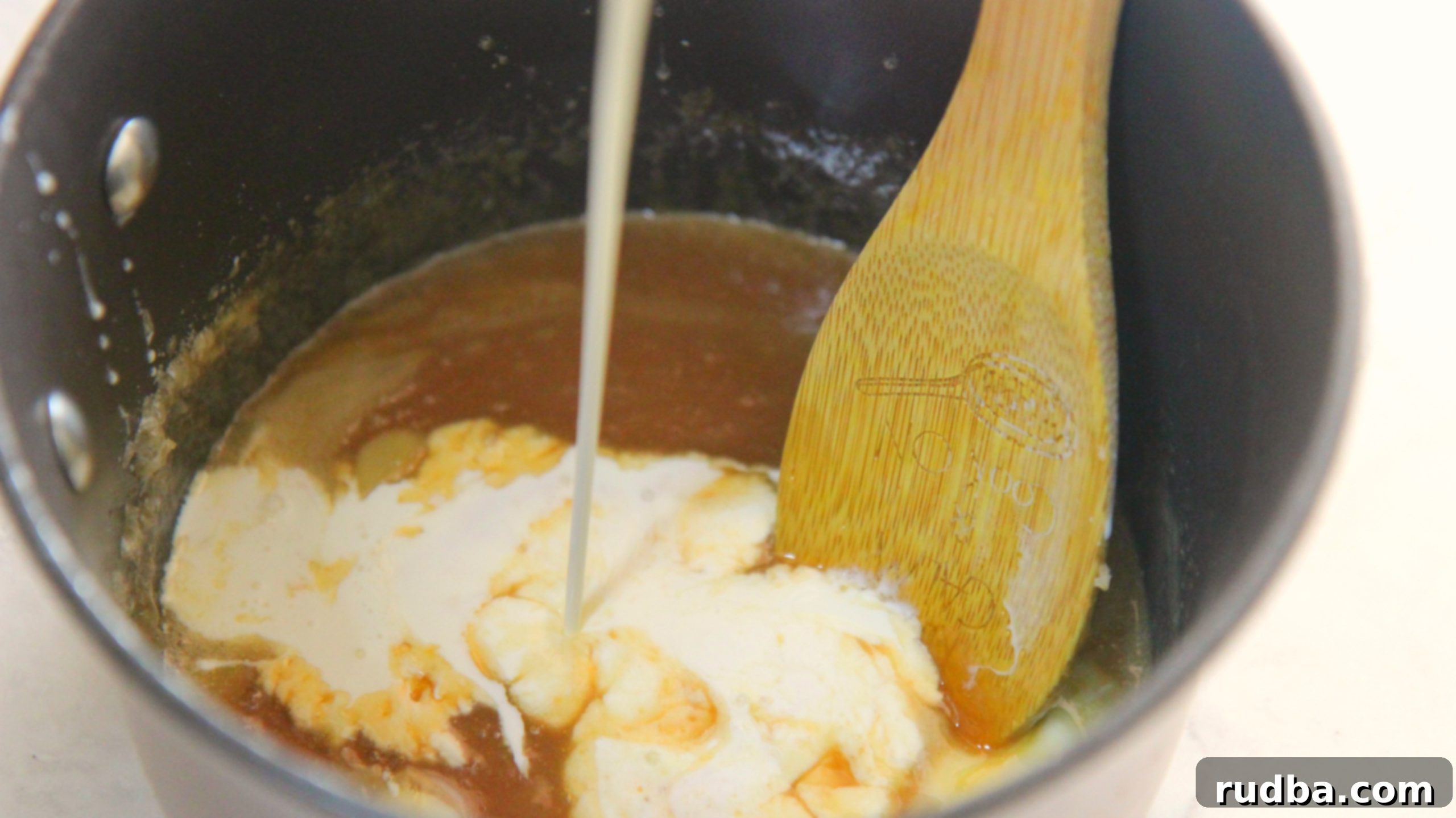 A saucepan on the stove with ingredients for caramel sauce, including heavy cream and butter.