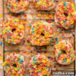 Eight colorful fruity pebble donuts arranged neatly on a wire cooling rack
