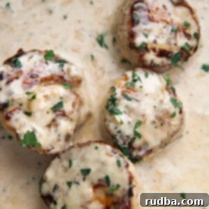 Close-up of four creamy garlic scallops in sauce.