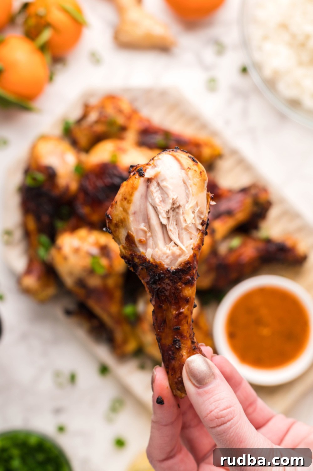 A hand holding a perfectly cooked, bitten air fryer chicken drumstick, showing its juicy interior and crispy skin.