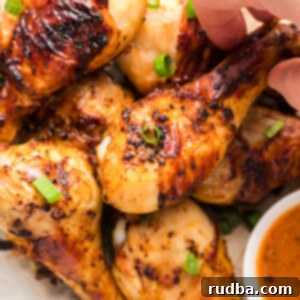 Crispy Air Fryer Chicken Drumsticks 5 air fryer chicken drumsticks with a dip on the side and scallions on top.
