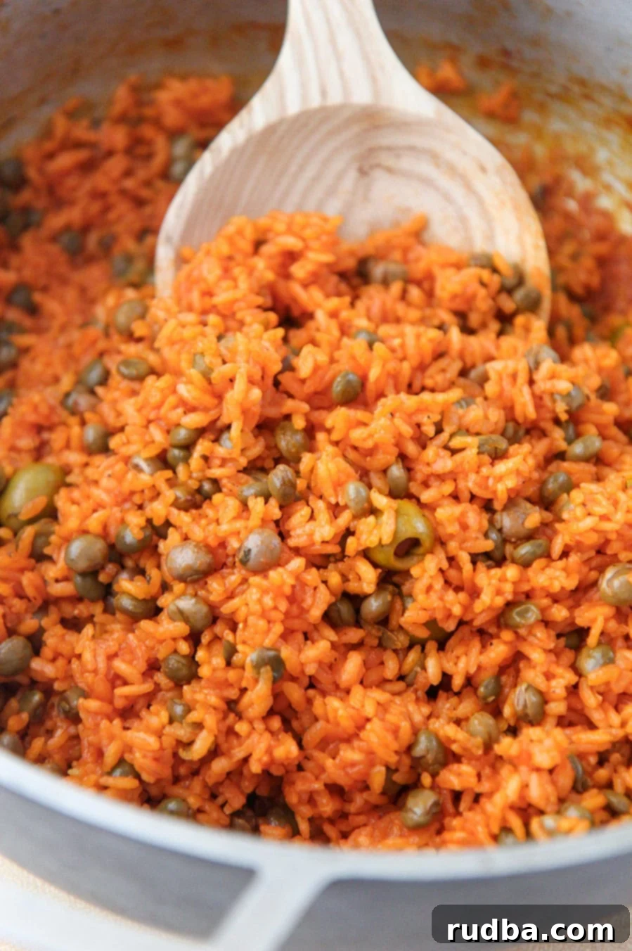 Arroz con Gandules - Rice and Pigeon Peas 2 arroz con gandules in a large pot with a wooden spoon.