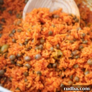 Arroz con Gandules - Rice and Pigeon Peas 5 arroz con gandules in a large pot with a wooden spoon.