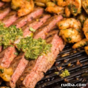 slices of steak with chimichurri on top and shrimp on the side.