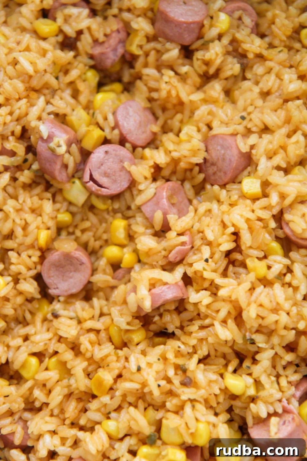A close-up view of fluffy Arroz con Salchichas in a bowl, showcasing the yellow rice, corn, and sausage pieces.