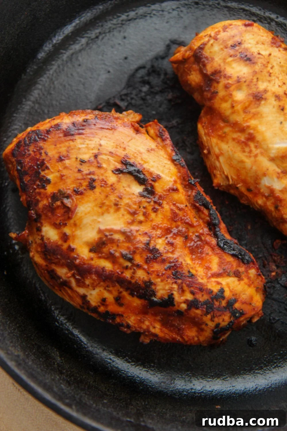 Restaurant Style Chipotle Chicken 2 Two chipotle chicken breasts in a cast iron skillet, perfectly cooked and ready to be served or chopped.