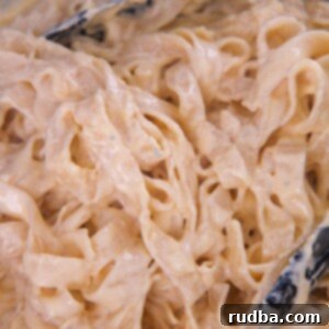 four cheese pasta in a skillet with tongs up close.