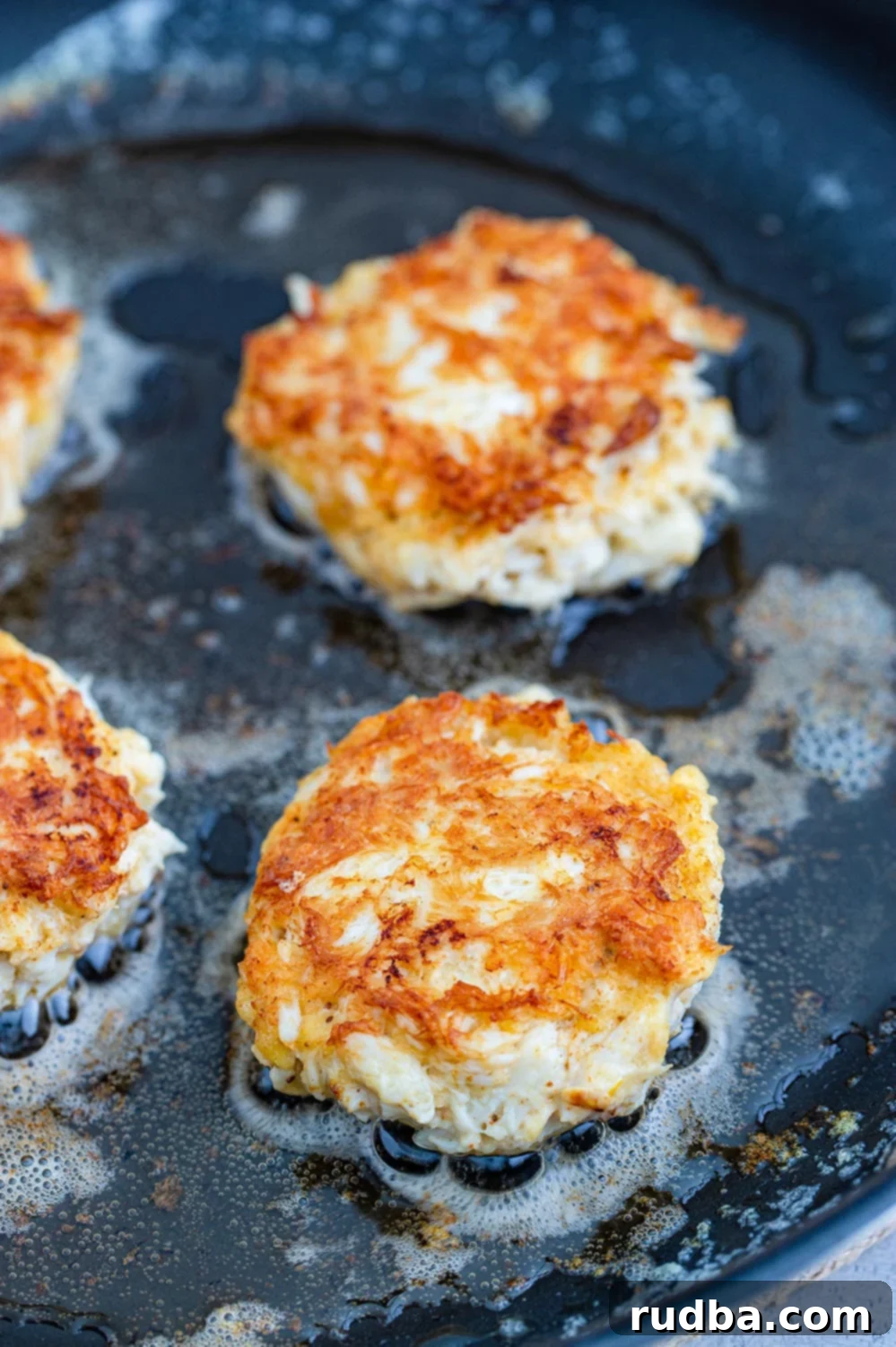 Golden Crab Cakes with Zesty Remoulade 5 crab cakes frying in a skillet.