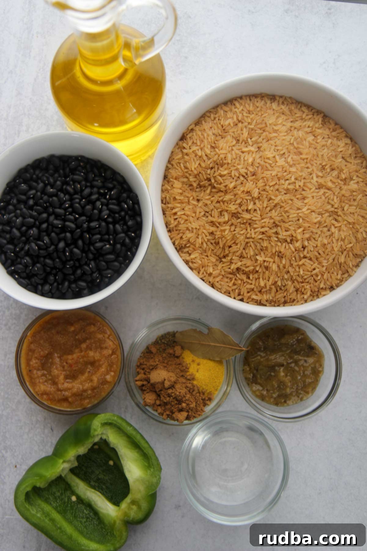 Classic Cuban Black Beans and Rice 2 ingredients for congri, dried black beans, brown rice, small bowls with spices, vinegar, bay leaf, sofrito, and recaito. Oil and a green bell pepper.