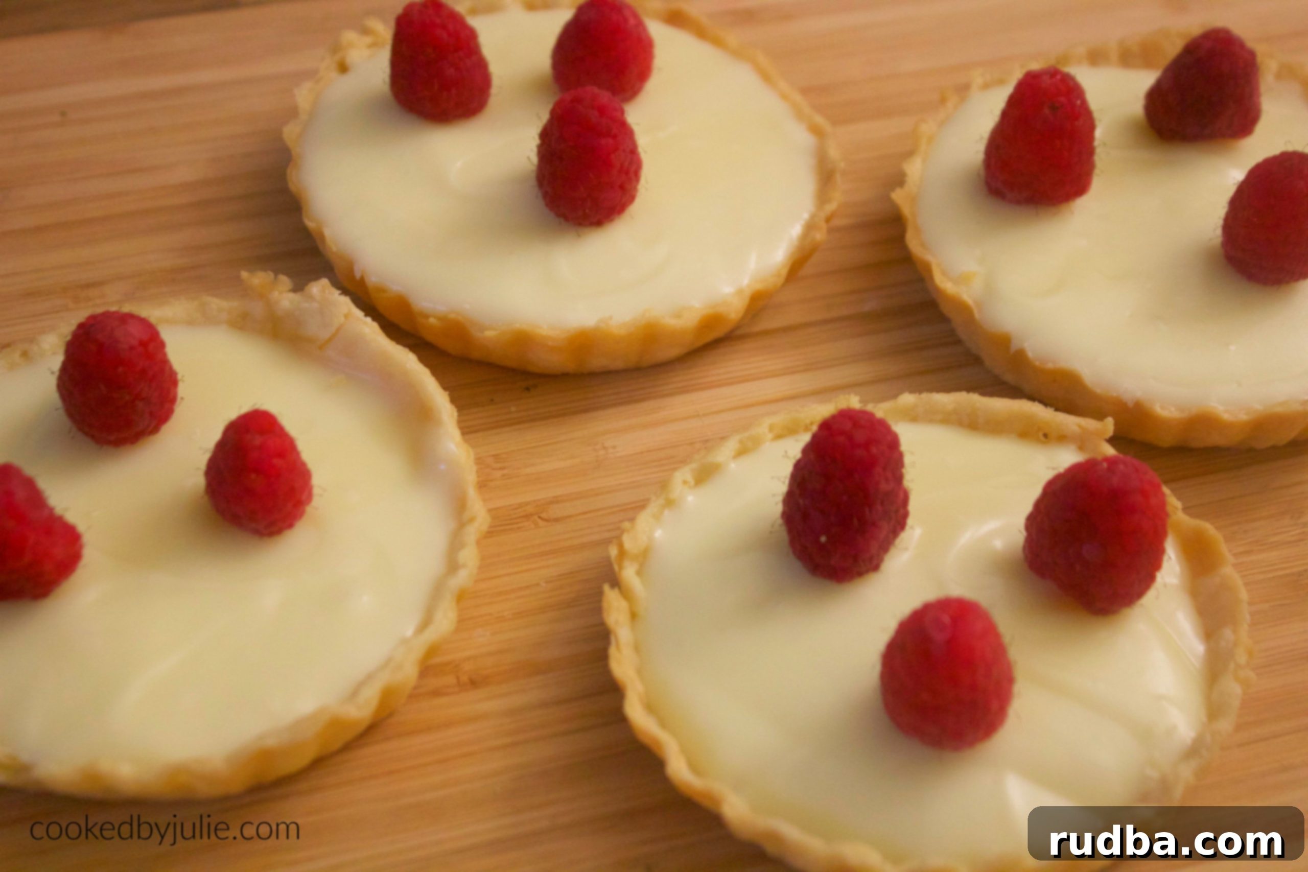 Close-up of a white chocolate tart with a sprinkle of berries, highlighting the smooth, creamy filling and flaky crust.