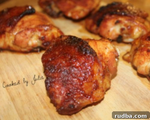 Five spicy honey baked chicken thighs on a wooden board. One chicken thigh up close.