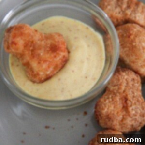 A close-up of air-fried frozen chicken nuggets alongside a bowl of creamy honey mustard, showcasing their crispy texture.