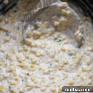 Velvety Slow Cooker Creamed Corn 2 slow cooker creamed corn with a wooden spoon.