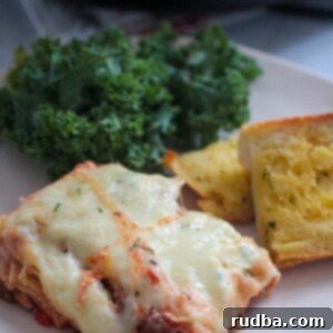 Crockpot Lasagna 2 A slice of lasagna with garlic bread and kale salad on the side.