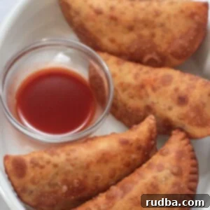 Zesty Beef and Melted Cheese Empanadas 2 Four spicy beef and cheese empanadas with hot sauce on the side.
