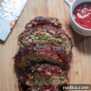 Perfect Air Fryer Turkey Meatloaf 2 sliced meatloaf on a wooden board with a knife and ketchup on the side.