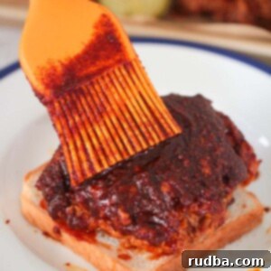 Nashville hot chicken on a slice of white bread and an orange brush.